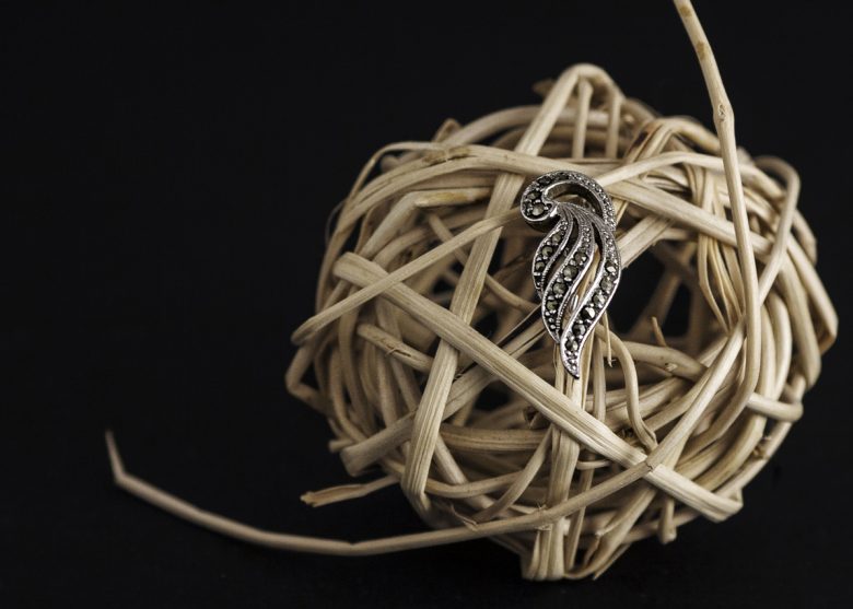 Photographie d'un broche en métal sur une boule de rotin.